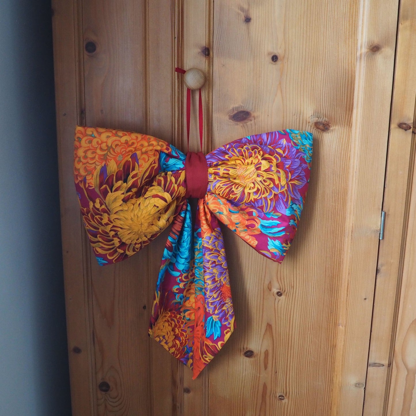 Handmade large padded decorative hanging bow - orange/purple floral